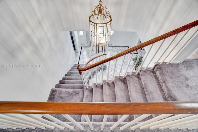 staircase with a notable chandelier