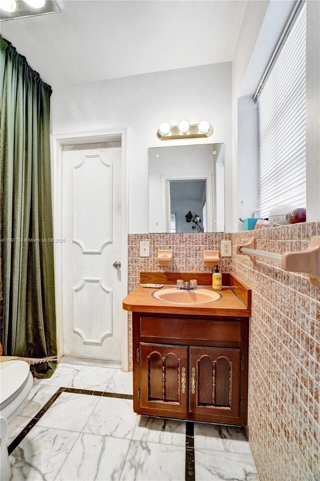 bathroom featuring vanity and tile walls