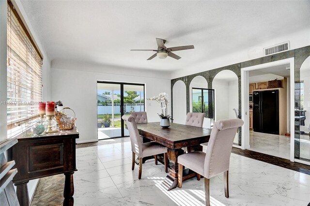 dining space with ceiling fan, a water view, and a textured ceiling