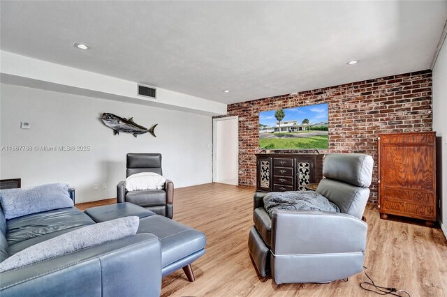 living room with light hardwood / wood-style flooring and brick wall