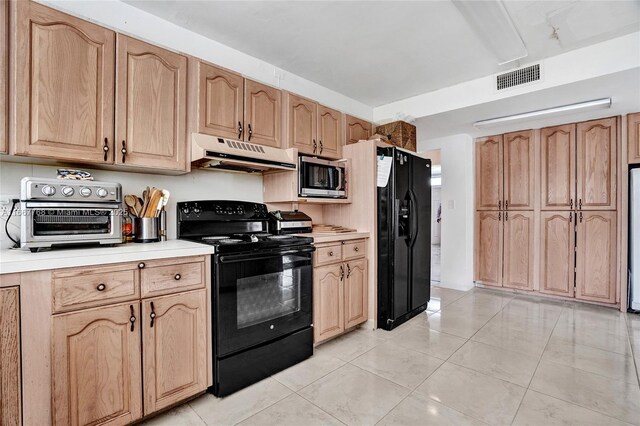 kitchen with light tile patterned flooring and black appliances