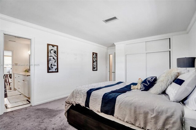 carpeted bedroom featuring ensuite bath and ornamental molding