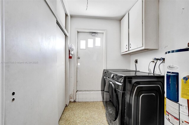 laundry area featuring washing machine and clothes dryer, water heater, and cabinets