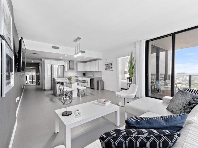 living room with a wall of windows, sink, and light tile patterned floors