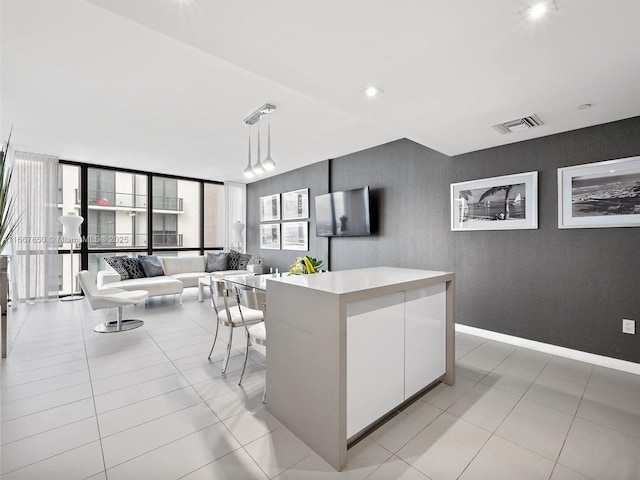 kitchen with plenty of natural light, a center island, white cabinets, light tile patterned flooring, and decorative light fixtures