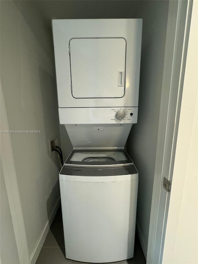 laundry area featuring tile patterned flooring and stacked washing maching and dryer