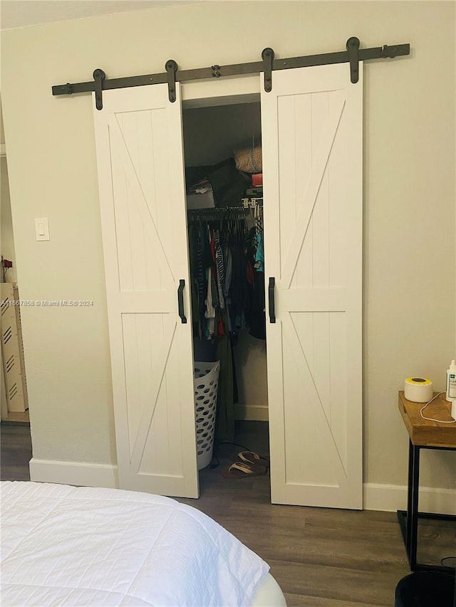 bedroom featuring a barn door, dark wood-type flooring, a walk in closet, and a closet