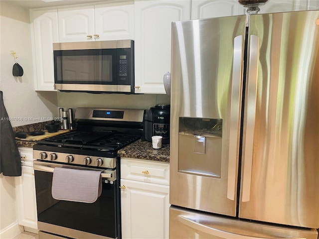 kitchen featuring dark stone countertops, white cabinetry, and stainless steel appliances