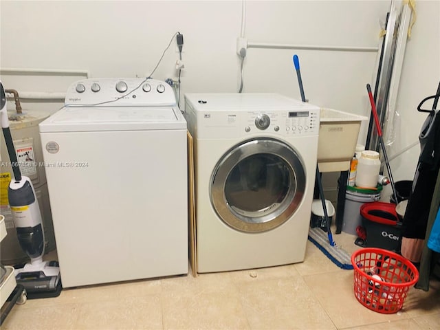 clothes washing area with water heater, light tile patterned flooring, and washing machine and clothes dryer