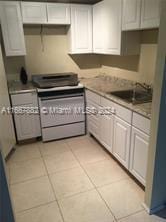 kitchen featuring white cabinets, electric stove, light tile patterned floors, and sink