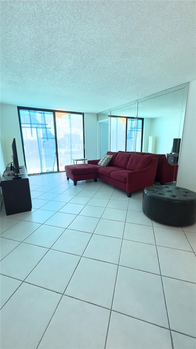 living room with expansive windows, a textured ceiling, and light tile patterned flooring