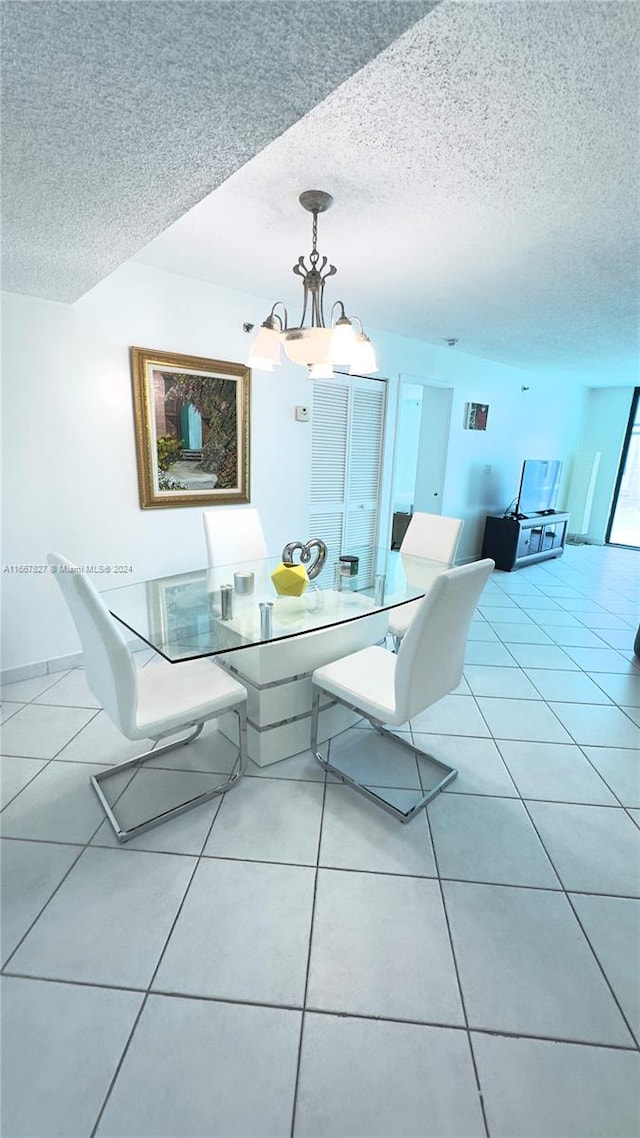 tiled dining room with a textured ceiling and a notable chandelier