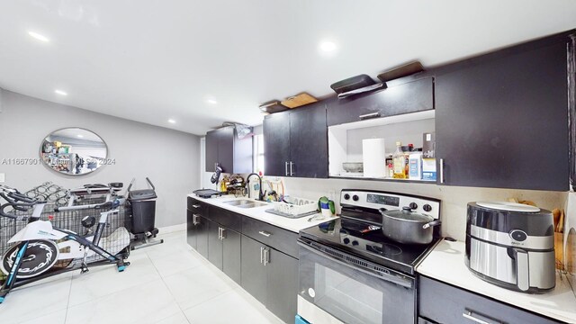 kitchen featuring stainless steel range with electric stovetop, light tile patterned floors, and sink