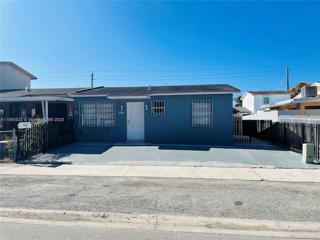 view of front facade with a fenced front yard, central AC unit, and stucco siding