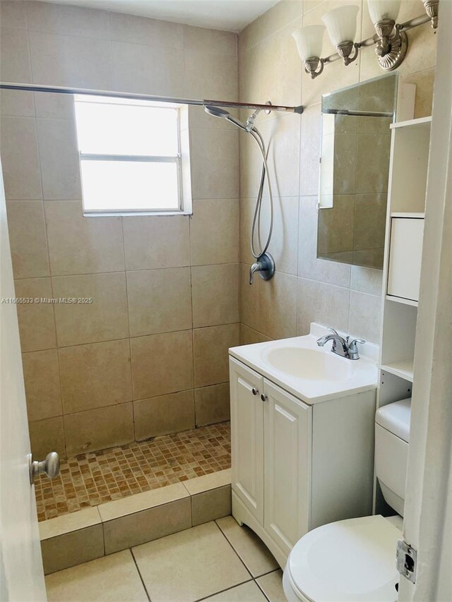 bathroom featuring toilet, vanity, tasteful backsplash, tile patterned floors, and tiled shower