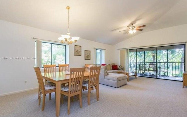 carpeted dining space featuring ceiling fan with notable chandelier, a wealth of natural light, and lofted ceiling