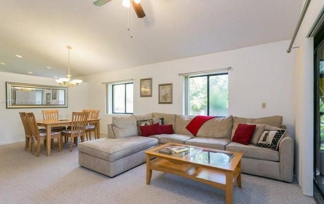 carpeted living room featuring ceiling fan with notable chandelier and a wealth of natural light