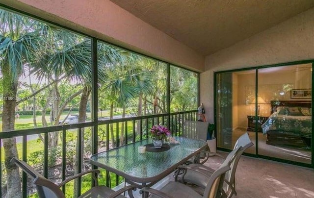 sunroom / solarium featuring vaulted ceiling and a healthy amount of sunlight