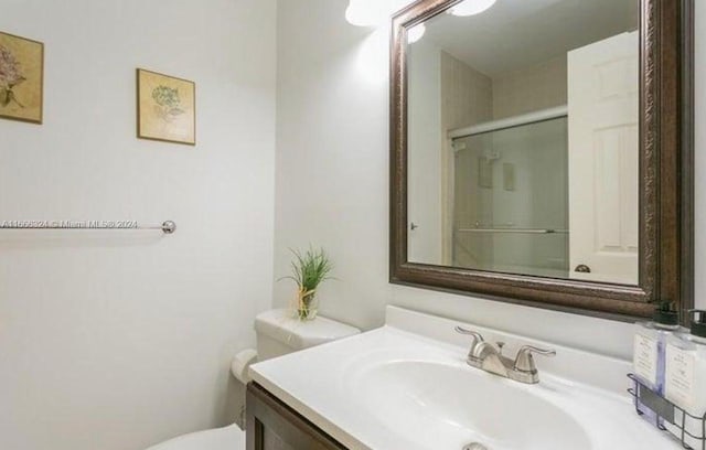 bathroom with walk in shower, vanity, and toilet