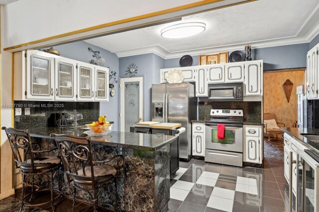 kitchen with appliances with stainless steel finishes, ornamental molding, a peninsula, and tasteful backsplash