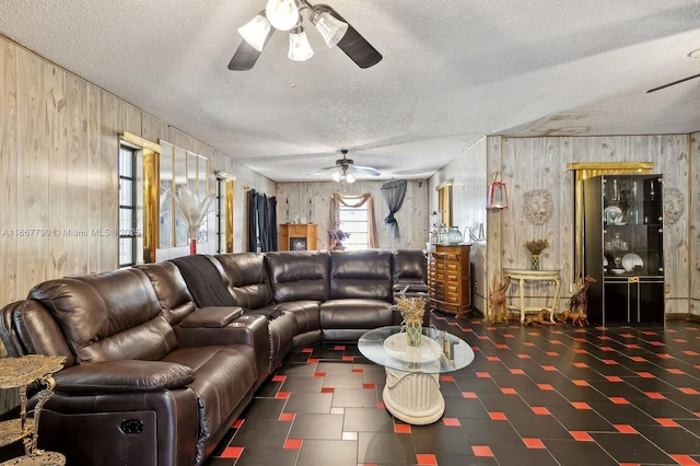 living room featuring a textured ceiling, ceiling fan, and wood walls