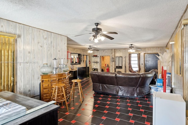 living area with a textured ceiling, a dry bar, and wood walls