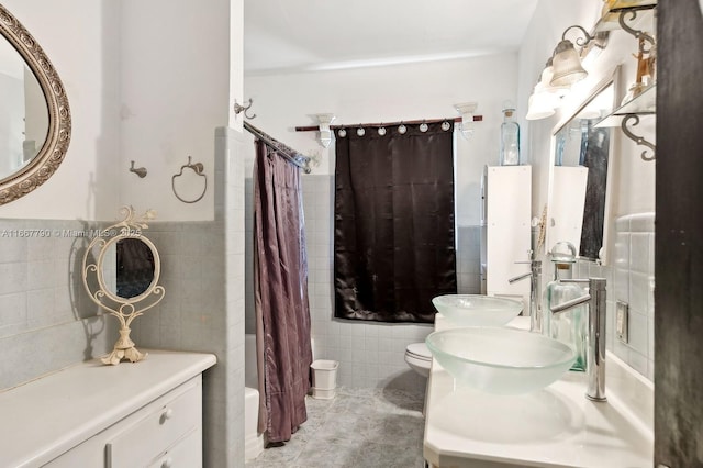 bathroom with toilet, a wainscoted wall, tile walls, tile patterned floors, and shower / bath combination with curtain