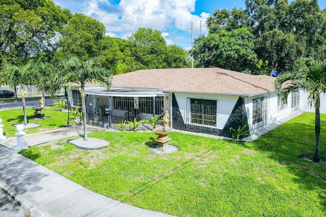 view of front of house with a front lawn, roof with shingles, and stucco siding