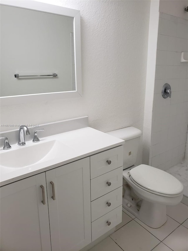 bathroom with a tile shower, tile patterned flooring, vanity, and toilet