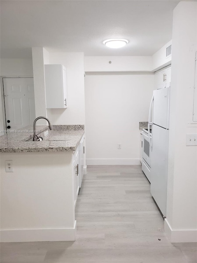 kitchen with light stone countertops, light hardwood / wood-style floors, white appliances, and white cabinetry