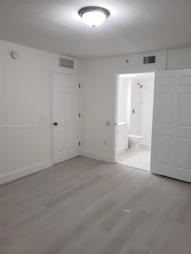 spare room featuring light wood-type flooring and a textured ceiling