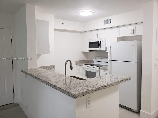 kitchen with visible vents, a sink, white appliances, a peninsula, and light stone countertops