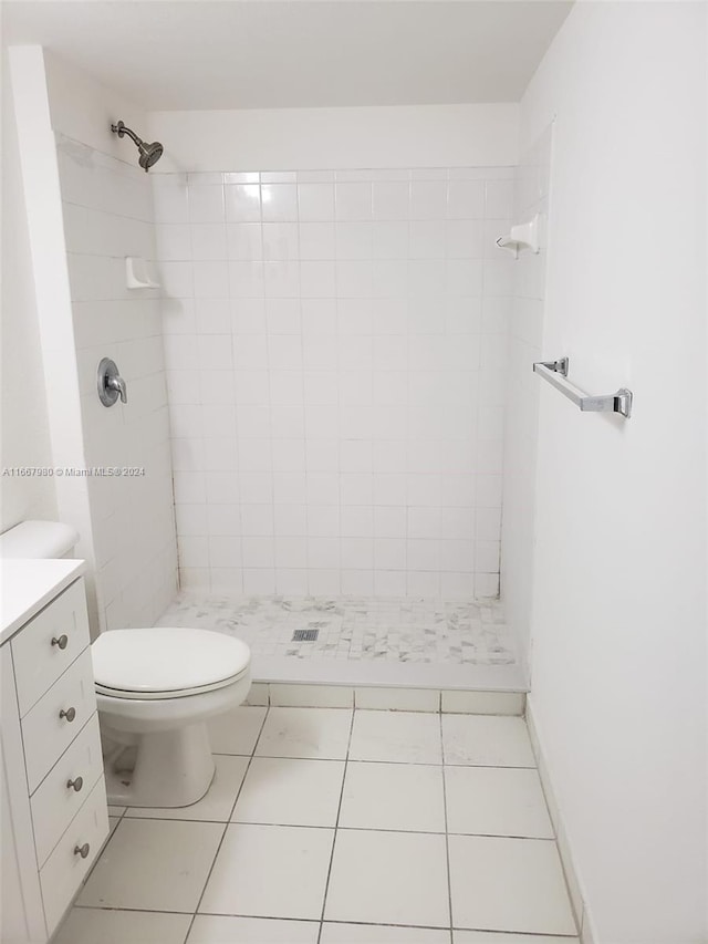 bathroom featuring tile patterned flooring, tiled shower, vanity, and toilet