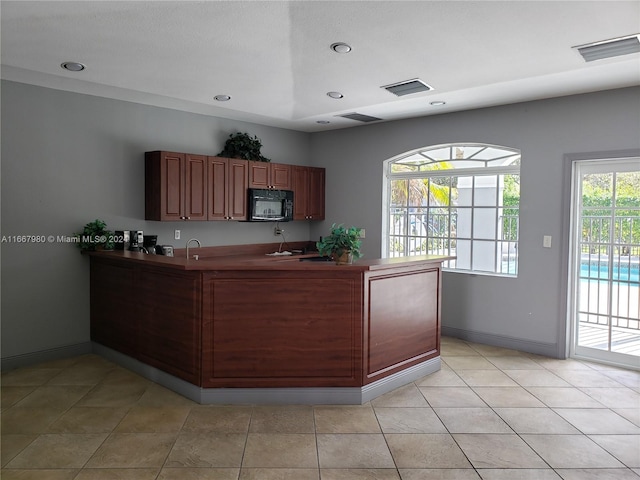 kitchen featuring sink, kitchen peninsula, and light tile patterned flooring