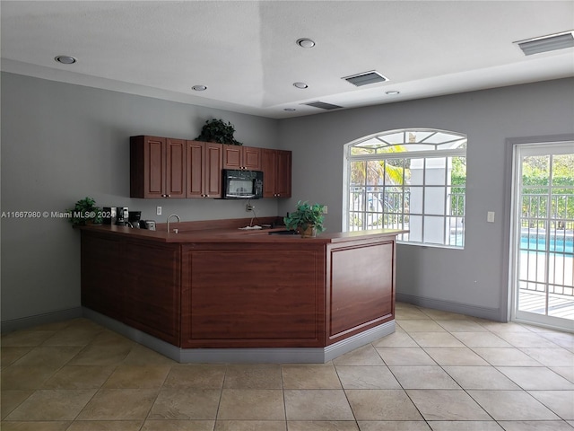 kitchen featuring black microwave, visible vents, baseboards, and a sink
