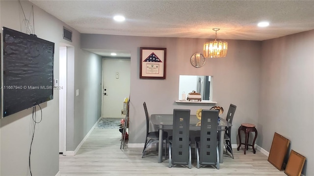 dining room featuring a textured ceiling, light hardwood / wood-style floors, and a chandelier