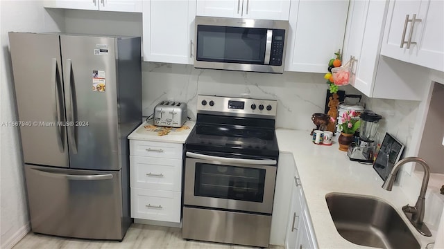 kitchen with light stone counters, sink, white cabinetry, decorative backsplash, and appliances with stainless steel finishes