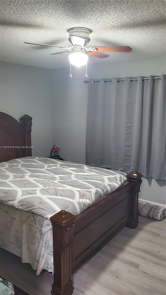 bedroom featuring ceiling fan, a textured ceiling, and light wood-type flooring