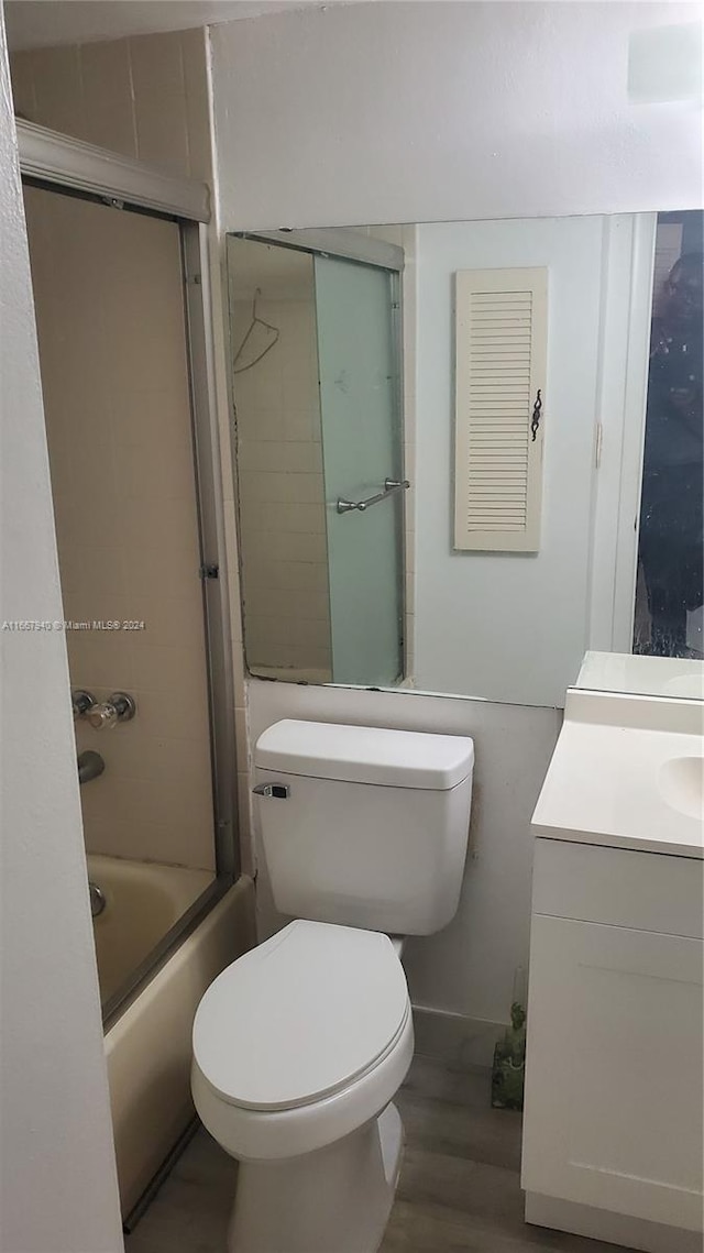 full bathroom featuring enclosed tub / shower combo, hardwood / wood-style floors, vanity, and toilet