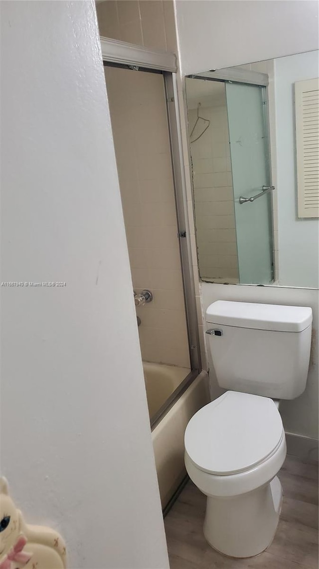 bathroom with shower / bath combination with glass door, hardwood / wood-style flooring, and toilet