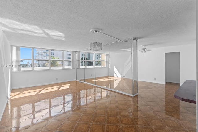 empty room with ceiling fan and a textured ceiling