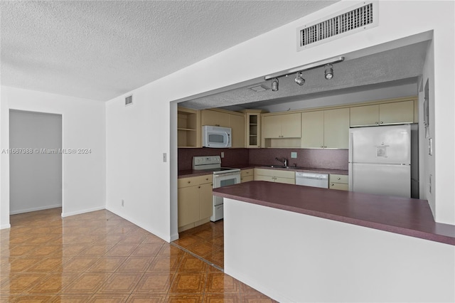 kitchen with a textured ceiling, white appliances, sink, cream cabinets, and backsplash