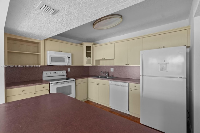 kitchen featuring sink, white appliances, a textured ceiling, cream cabinetry, and hardwood / wood-style flooring