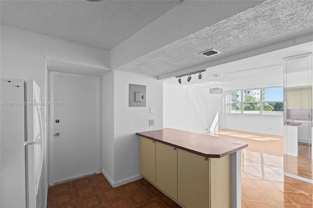 kitchen with kitchen peninsula, electric panel, white refrigerator, track lighting, and a textured ceiling