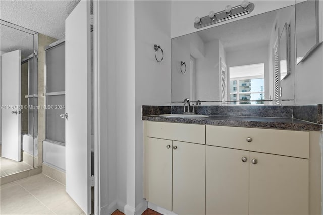 bathroom with tile patterned flooring, walk in shower, vanity, and a textured ceiling