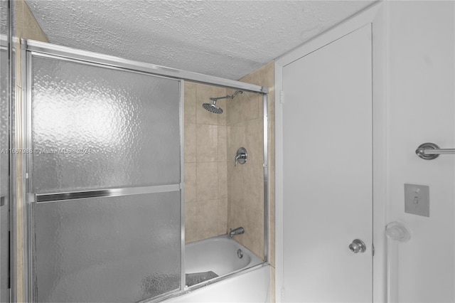 bathroom featuring enclosed tub / shower combo and a textured ceiling