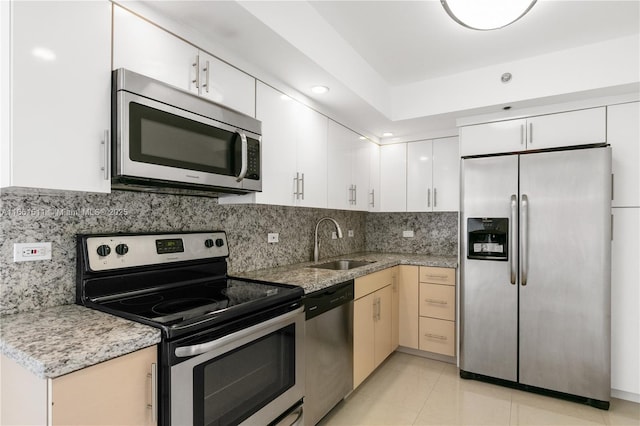 kitchen featuring sink, stainless steel appliances, tasteful backsplash, white cabinets, and light tile patterned flooring