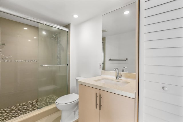 bathroom featuring vanity, toilet, and a shower with door