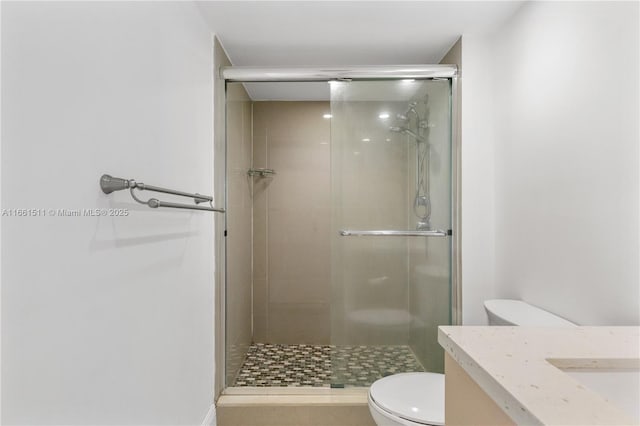 bathroom featuring tile patterned flooring, a shower with door, vanity, and toilet