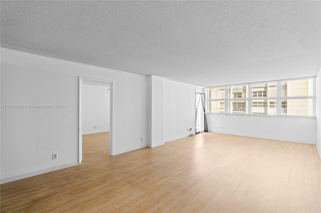 unfurnished room featuring light hardwood / wood-style flooring and a textured ceiling